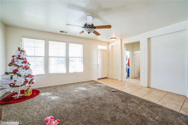 interior space featuring light carpet, visible vents, a ceiling fan, and light tile patterned flooring