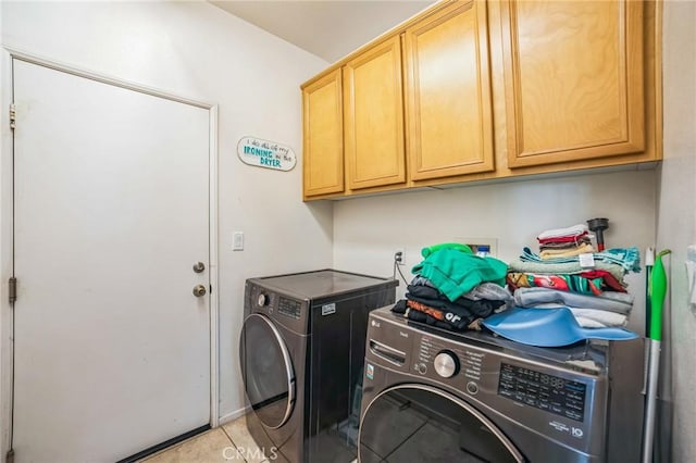 clothes washing area with cabinet space, washer and clothes dryer, and light tile patterned flooring