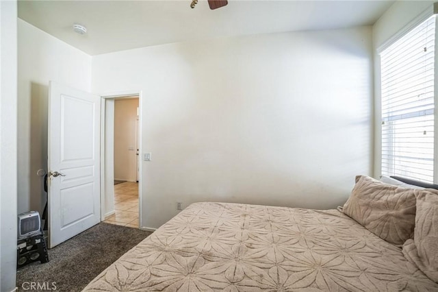 bedroom featuring light carpet, multiple windows, and a ceiling fan