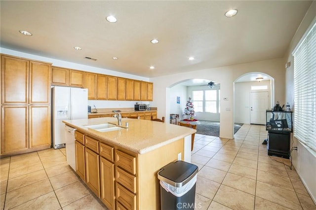 kitchen featuring ceiling fan, a center island with sink, light tile patterned flooring, sink, and white appliances