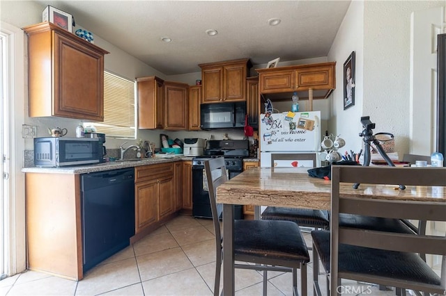 kitchen featuring light tile patterned floors, black appliances, and sink