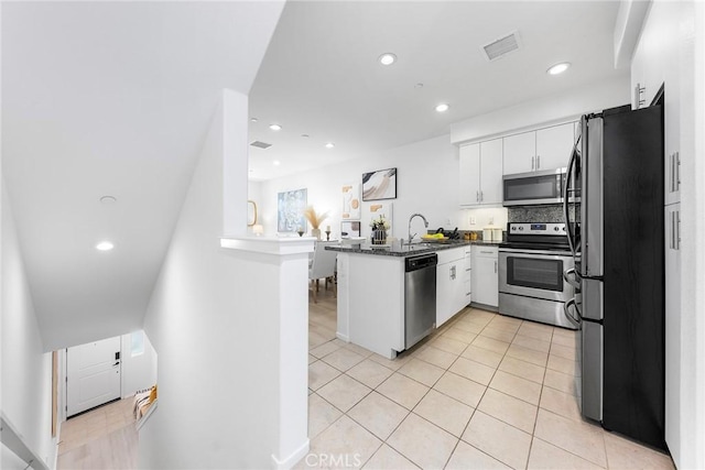 kitchen with white cabinets, appliances with stainless steel finishes, decorative backsplash, kitchen peninsula, and light tile patterned flooring