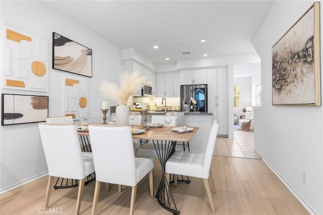 dining space with sink and light hardwood / wood-style flooring