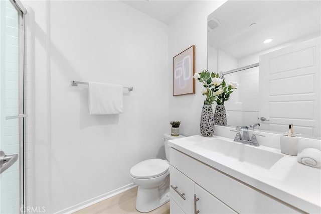 bathroom featuring a shower with door, toilet, and vanity