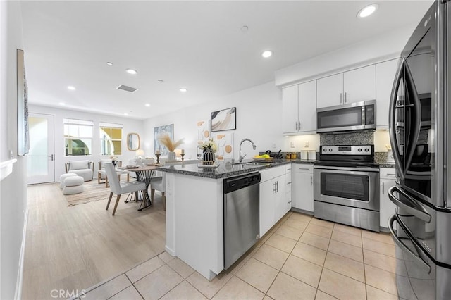 kitchen with kitchen peninsula, white cabinetry, sink, and stainless steel appliances