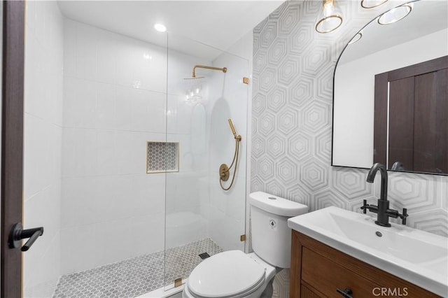 bathroom with toilet, vanity, and tiled shower