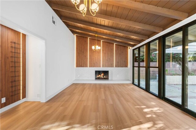 unfurnished living room featuring wood ceiling, hardwood / wood-style flooring, a notable chandelier, a fireplace, and lofted ceiling with beams