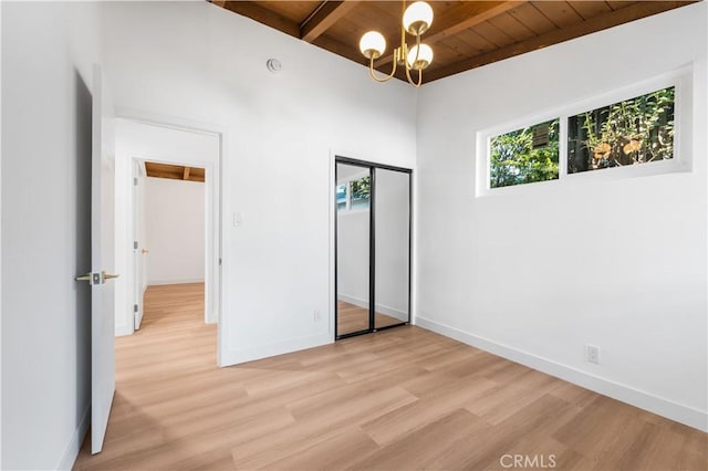 unfurnished bedroom with beam ceiling, light hardwood / wood-style flooring, a closet, and wooden ceiling