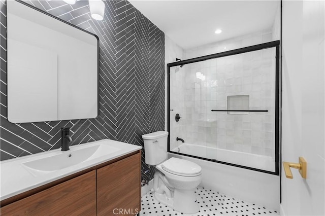 full bathroom with tile patterned floors, vanity, tile walls, toilet, and combined bath / shower with glass door