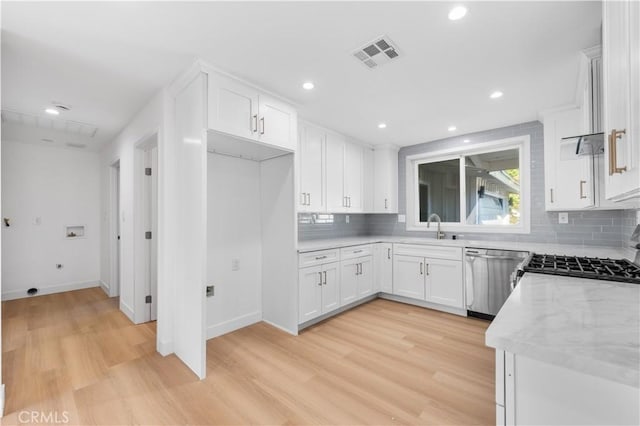 kitchen featuring white cabinetry, light stone countertops, stainless steel dishwasher, light hardwood / wood-style flooring, and sink