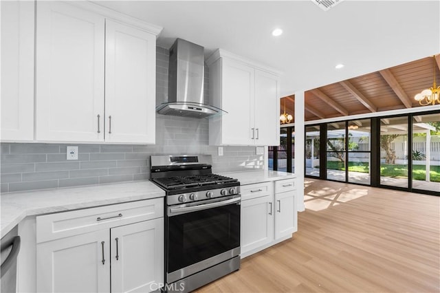 kitchen with stainless steel appliances, white cabinets, wall chimney exhaust hood, light hardwood / wood-style flooring, and light stone counters