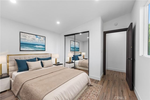 bedroom featuring hardwood / wood-style flooring, a closet, and vaulted ceiling