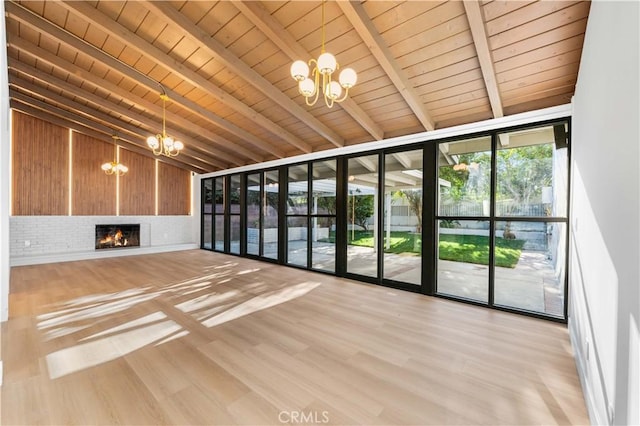 unfurnished living room with wood ceiling, a notable chandelier, light wood-type flooring, a fireplace, and beam ceiling