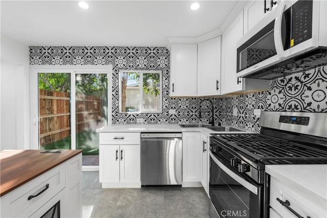 kitchen featuring backsplash, appliances with stainless steel finishes, sink, and white cabinetry