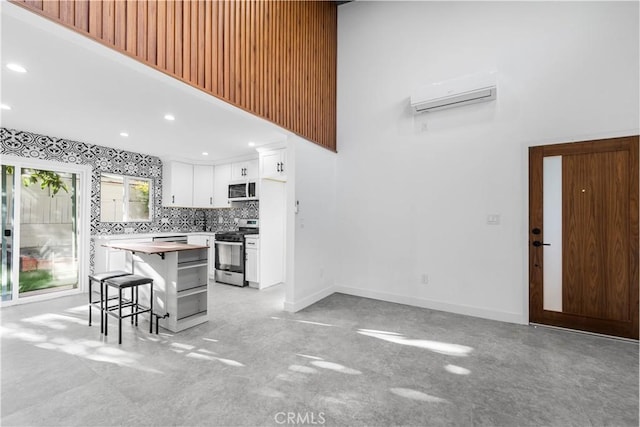 kitchen with a center island, a kitchen bar, decorative backsplash, appliances with stainless steel finishes, and white cabinets