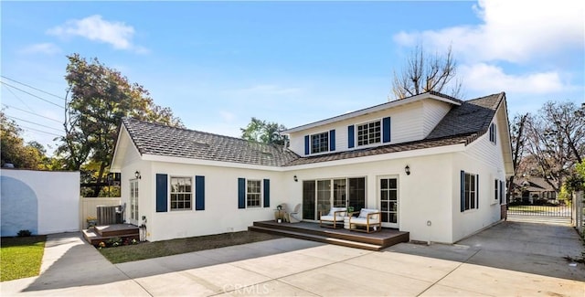 rear view of property featuring a wooden deck and a patio