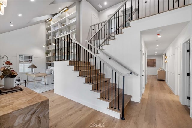 stairway with wood-type flooring and a towering ceiling