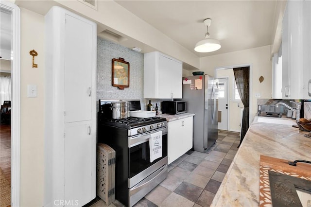 kitchen featuring backsplash, stainless steel appliances, sink, and white cabinets