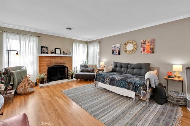 bedroom with crown molding, a fireplace, and hardwood / wood-style floors