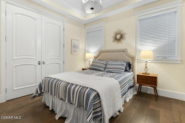 bedroom featuring a closet, dark hardwood / wood-style floors, and ornamental molding