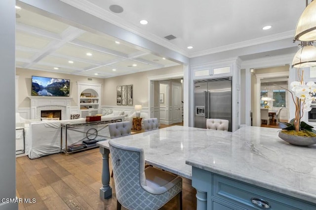 kitchen with built in fridge, light stone countertops, decorative light fixtures, a kitchen breakfast bar, and coffered ceiling