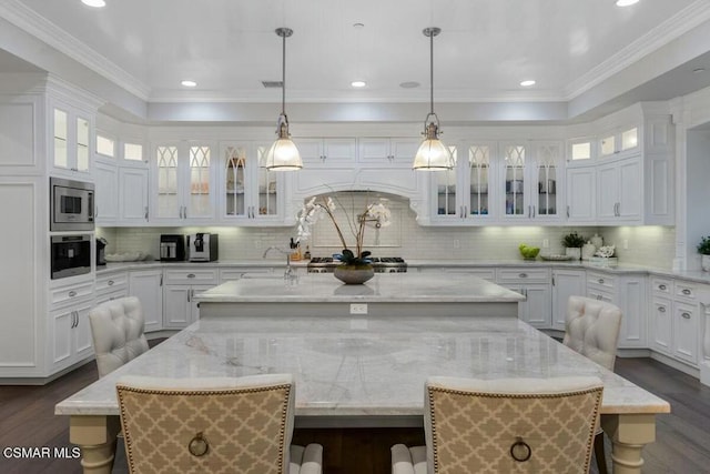 kitchen with a breakfast bar, a kitchen island with sink, and white cabinetry