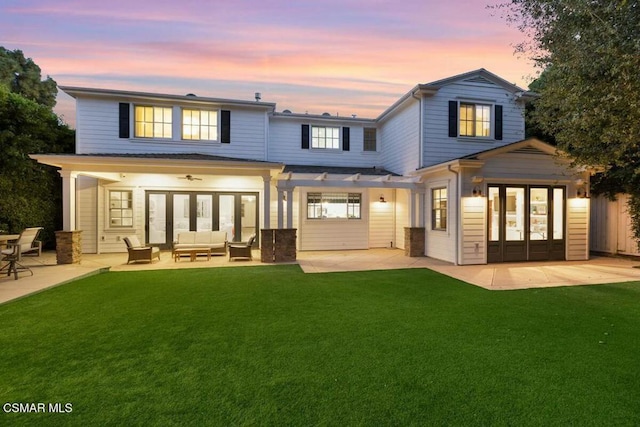 back house at dusk featuring outdoor lounge area, a yard, and french doors