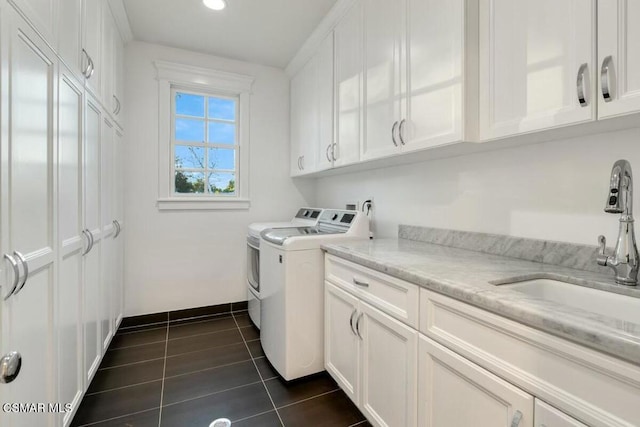 laundry room featuring washer and dryer, cabinets, dark tile patterned flooring, and sink