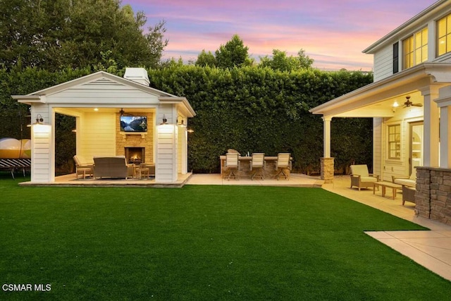 view of yard featuring exterior fireplace and a patio area