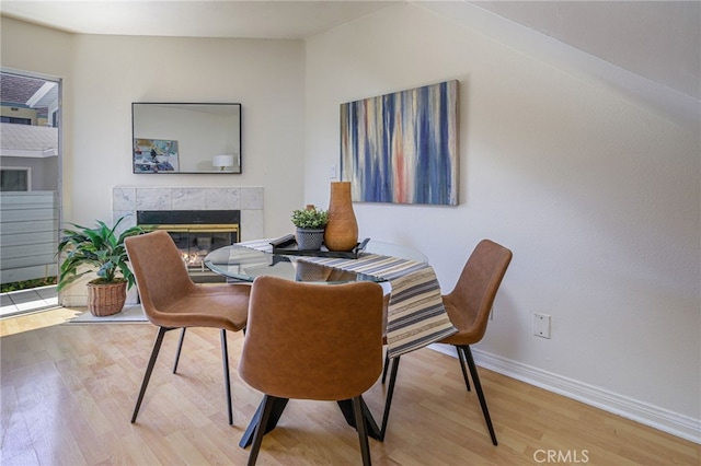 dining room with hardwood / wood-style floors and a tiled fireplace