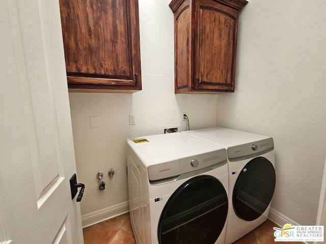 washroom featuring cabinets, light tile patterned floors, and washing machine and clothes dryer