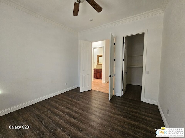 unfurnished bedroom with ceiling fan, dark wood-type flooring, a closet, and a walk in closet