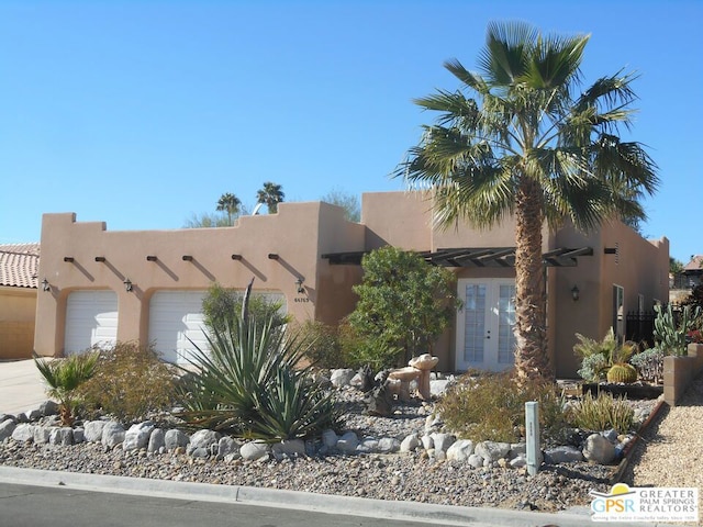 pueblo-style house featuring a garage and french doors