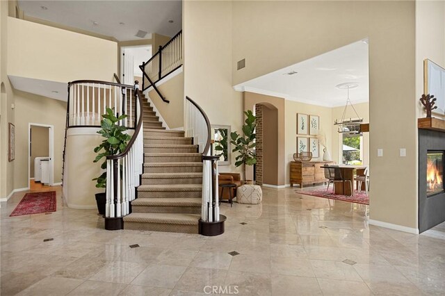 entrance foyer with a notable chandelier, crown molding, and a towering ceiling