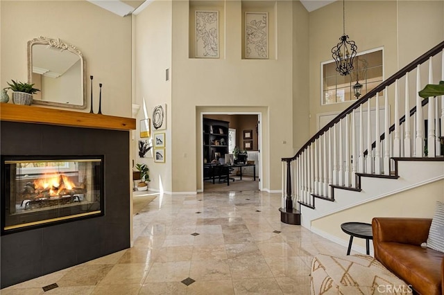 entrance foyer with a multi sided fireplace, a high ceiling, and a notable chandelier