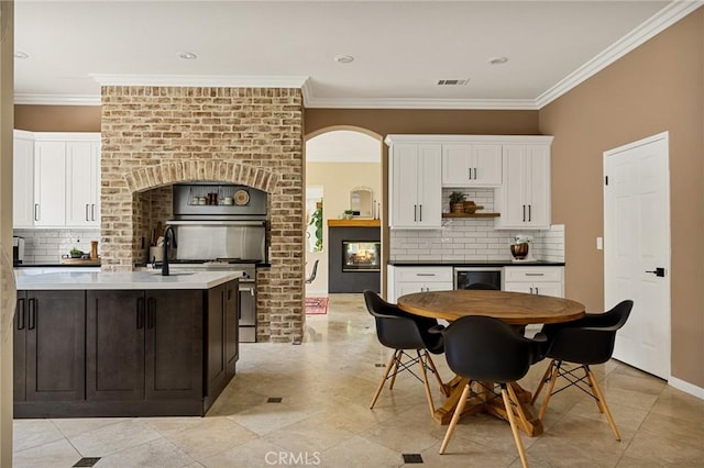 kitchen featuring beverage cooler, white cabinets, crown molding, and tasteful backsplash