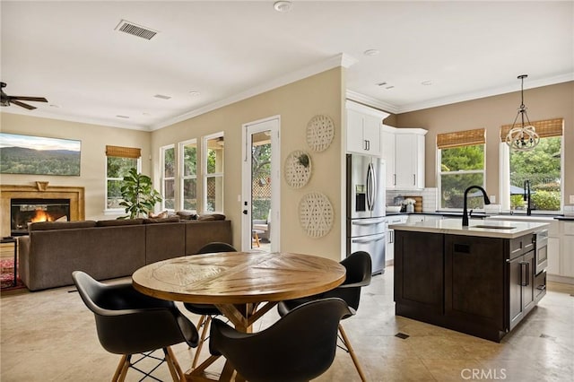 dining room featuring ceiling fan with notable chandelier, sink, and crown molding