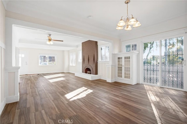 unfurnished living room featuring a brick fireplace, dark hardwood / wood-style flooring, and ceiling fan with notable chandelier