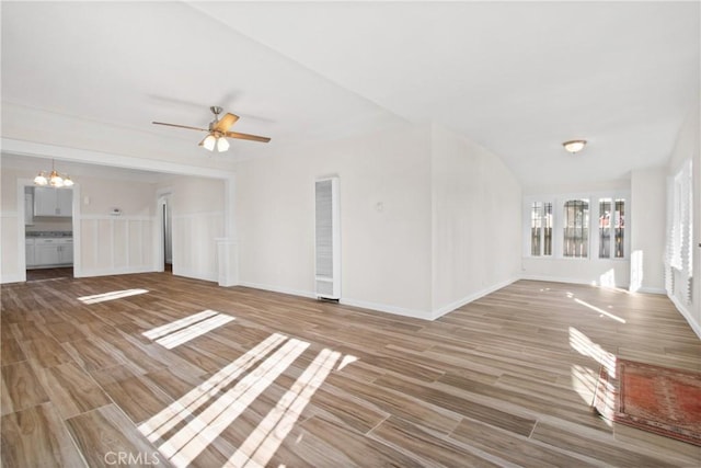 unfurnished living room featuring ceiling fan with notable chandelier and hardwood / wood-style floors