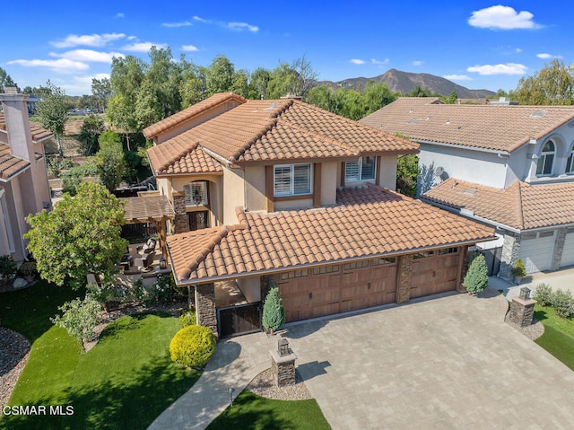 mediterranean / spanish-style home with a front lawn, a mountain view, and a garage