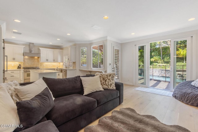 living room featuring light wood-type flooring, ornamental molding, and sink