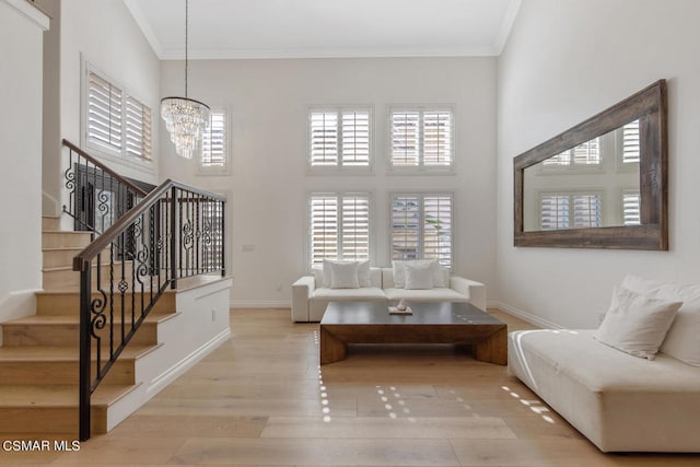 living room featuring light hardwood / wood-style floors, crown molding, and a notable chandelier