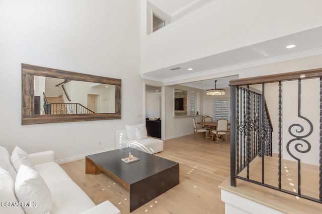 living room featuring light hardwood / wood-style floors, ornamental molding, and a notable chandelier