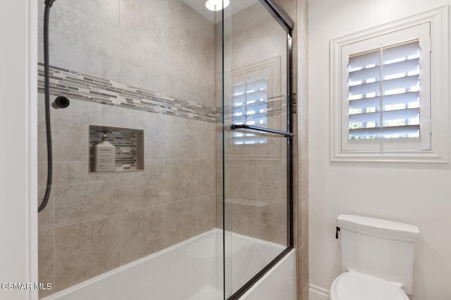 bathroom featuring toilet and combined bath / shower with glass door