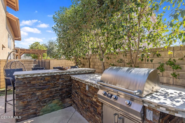 view of patio with exterior kitchen, exterior bar, grilling area, and a pergola