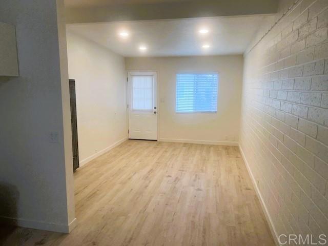 interior space featuring brick wall and light hardwood / wood-style flooring