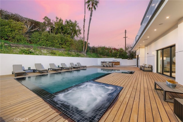 pool at dusk featuring a wooden deck