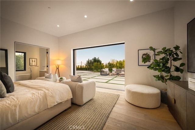 bedroom with light wood-type flooring, multiple windows, and access to outside