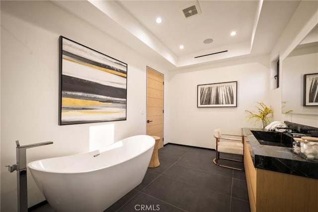 bathroom featuring a raised ceiling, vanity, a washtub, and tile patterned floors