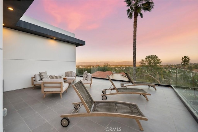 patio terrace at dusk featuring a balcony